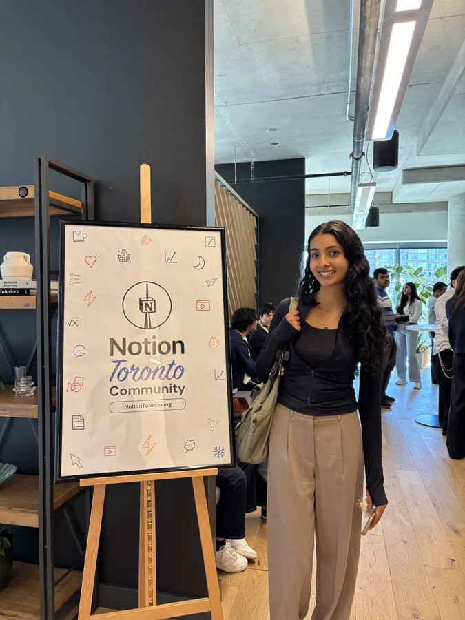 Khushi beside the sign at a Notion Toronto Community event